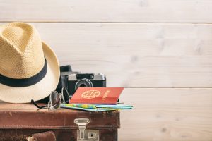 Travel accessories on an old suitcase - white wooden background