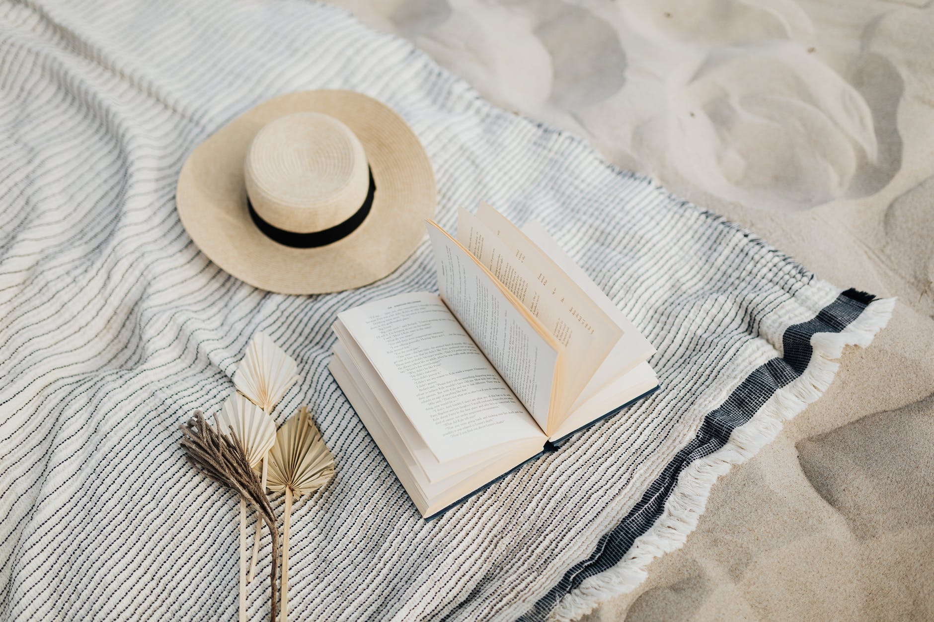 Hat and book on beach towel