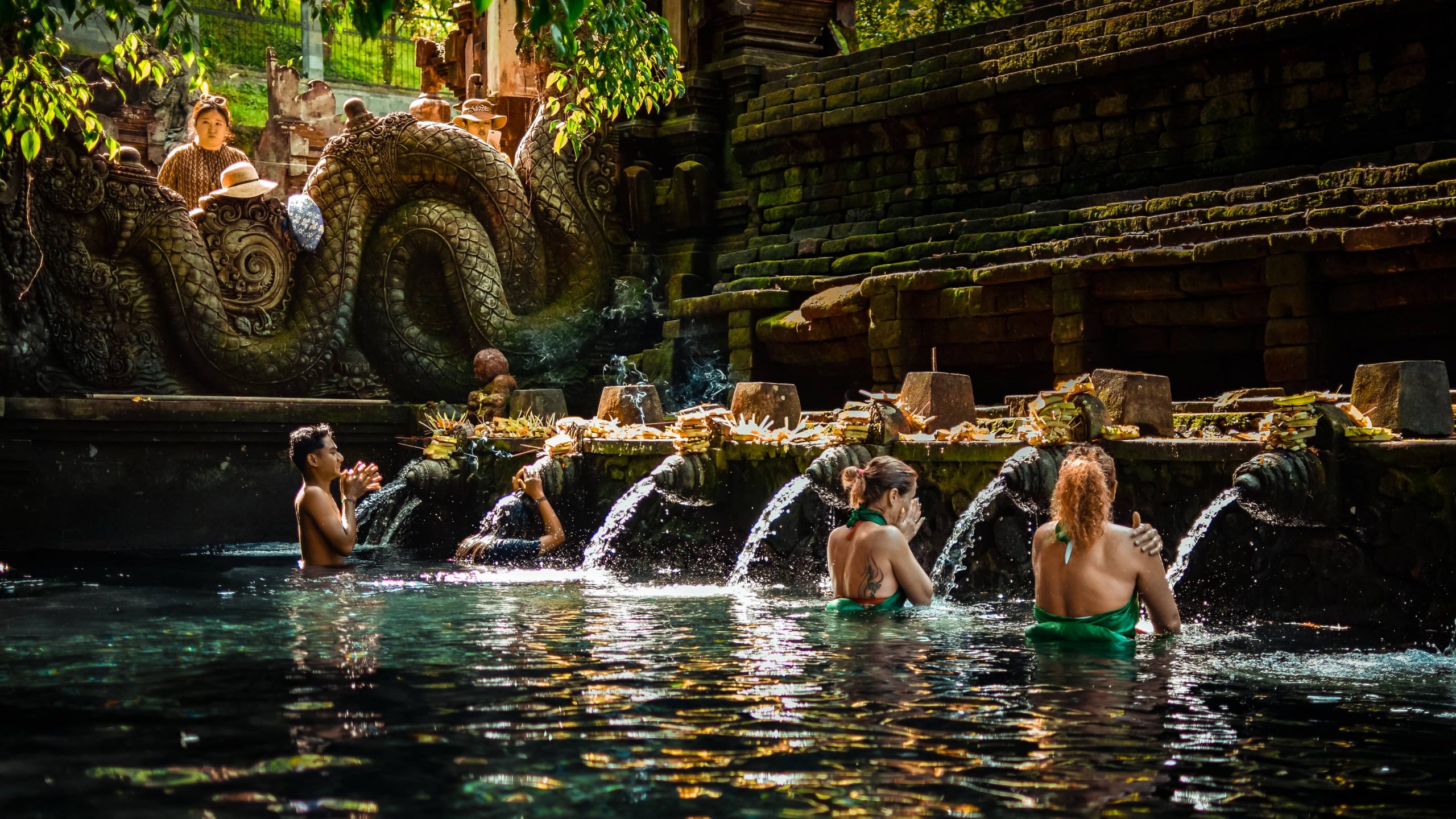 Tourists bathing in the waters of Tirta Empul Temple in Bali, Indonesia on a post about temple etiquette