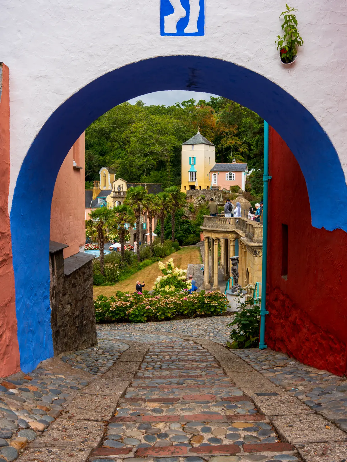 Portmeirion 3x4 View through a blue-painted arch towards the colourful buildings and gardens of Portmeirion.